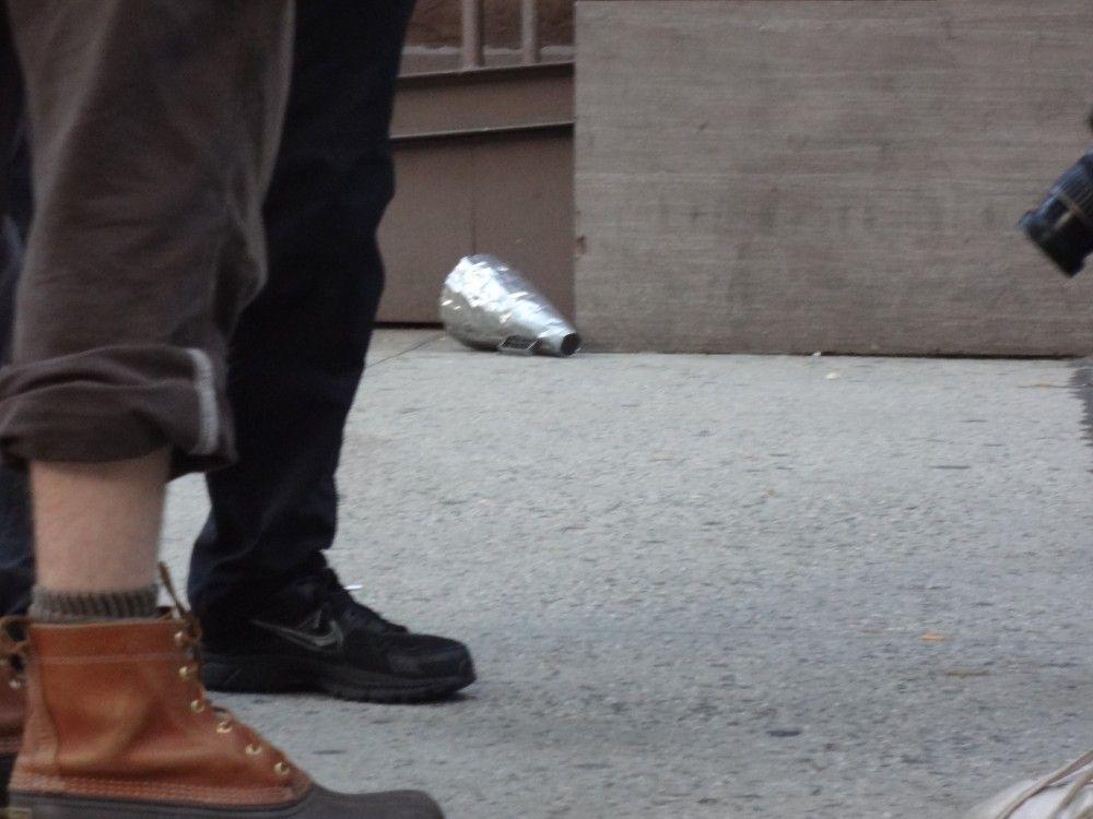 A metal megaphone discarded by a trashcan, surrounded by a student debt protest