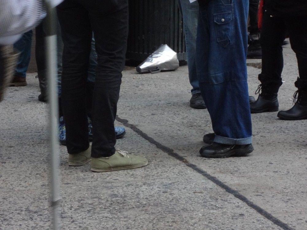 A metal megaphone discarded by a trashcan, surrounded by a student debt protest